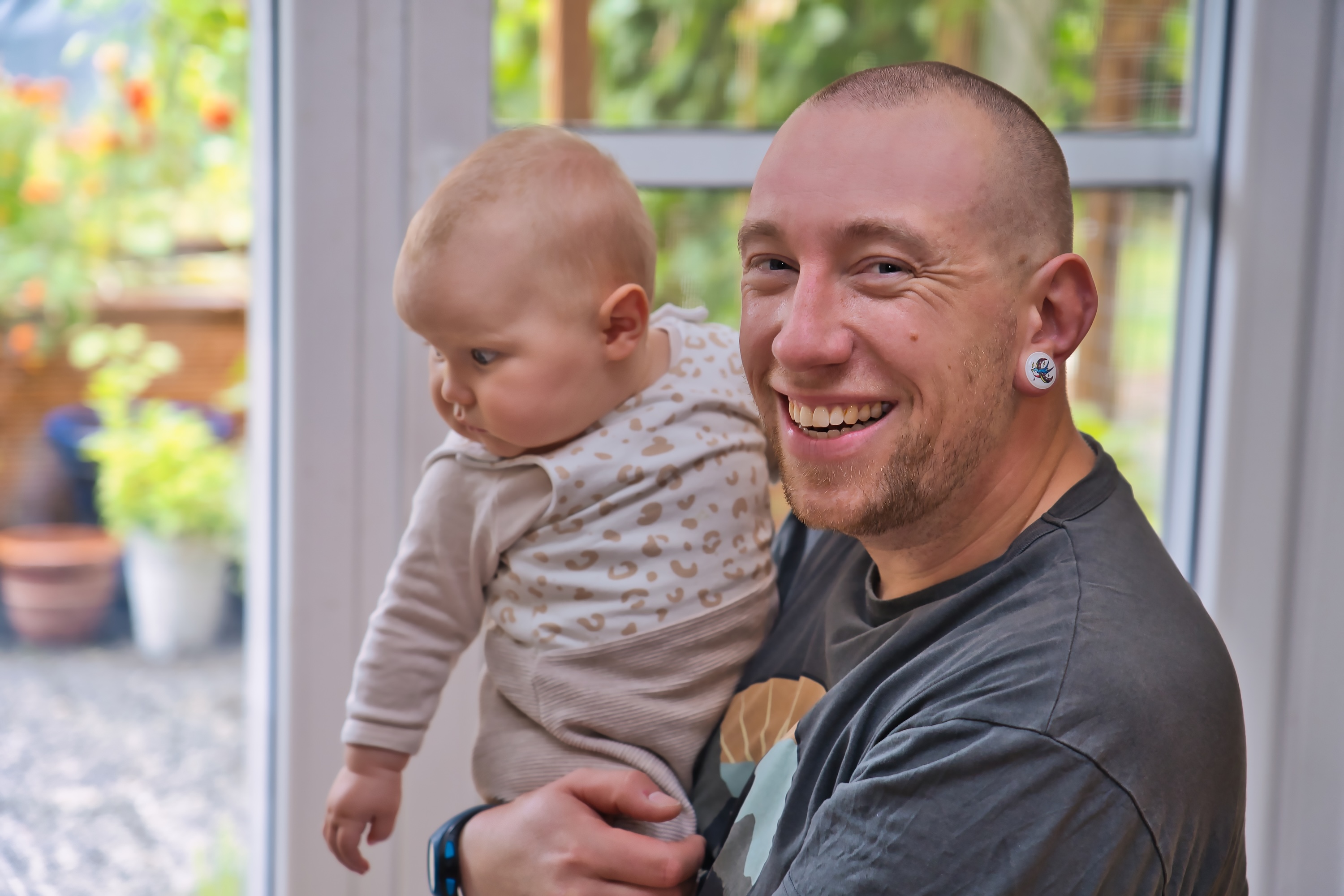 lächelnder Mann mit Baby auf dem Arm
